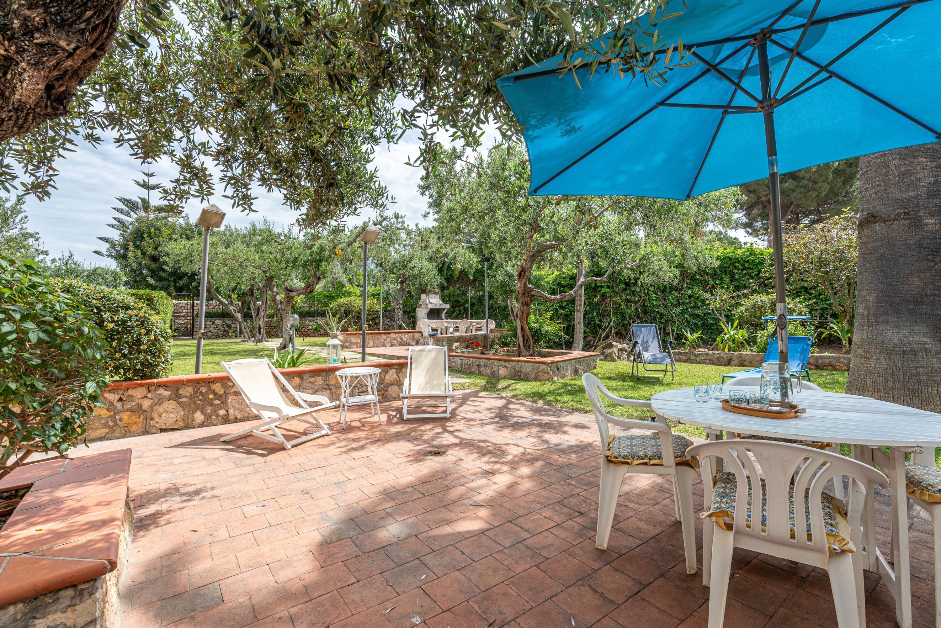 An outdoor patio with a table, chairs, and a blue umbrella.