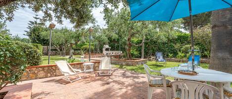 An outdoor patio with a table, chairs, and a blue umbrella.