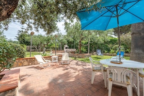 Un patio al aire libre con una mesa, sillas y un paraguas azul.