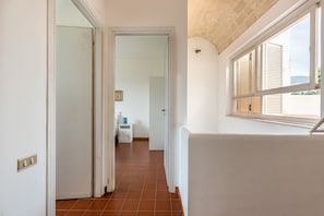 A hallway with a tiled floor, a white door, and a window with shutters. - The Hidden Olive Gem by Wonderful Italy (Terrasini)
