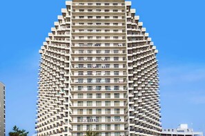 A high-rise building with a unique angular design, multiple balconies, and a clear sky. - Sea Watch 106- Oceanfront Escape with Pools, Arcade, Beach Access (Ocean City)