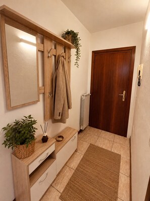 Ein Badezimmer mit einem Holztischchen, einem Handtuchhalter, einem Spiegel, einer Heizung und einer Tür.