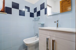 Un baño con azulejos azul claro, un lavamanos blanco y un bidé.