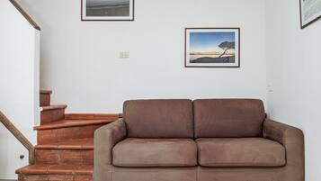 Ein braunes Sofa in einem Zimmer mit einer Treppe und zwei gerahmten Bildern an der Wand.