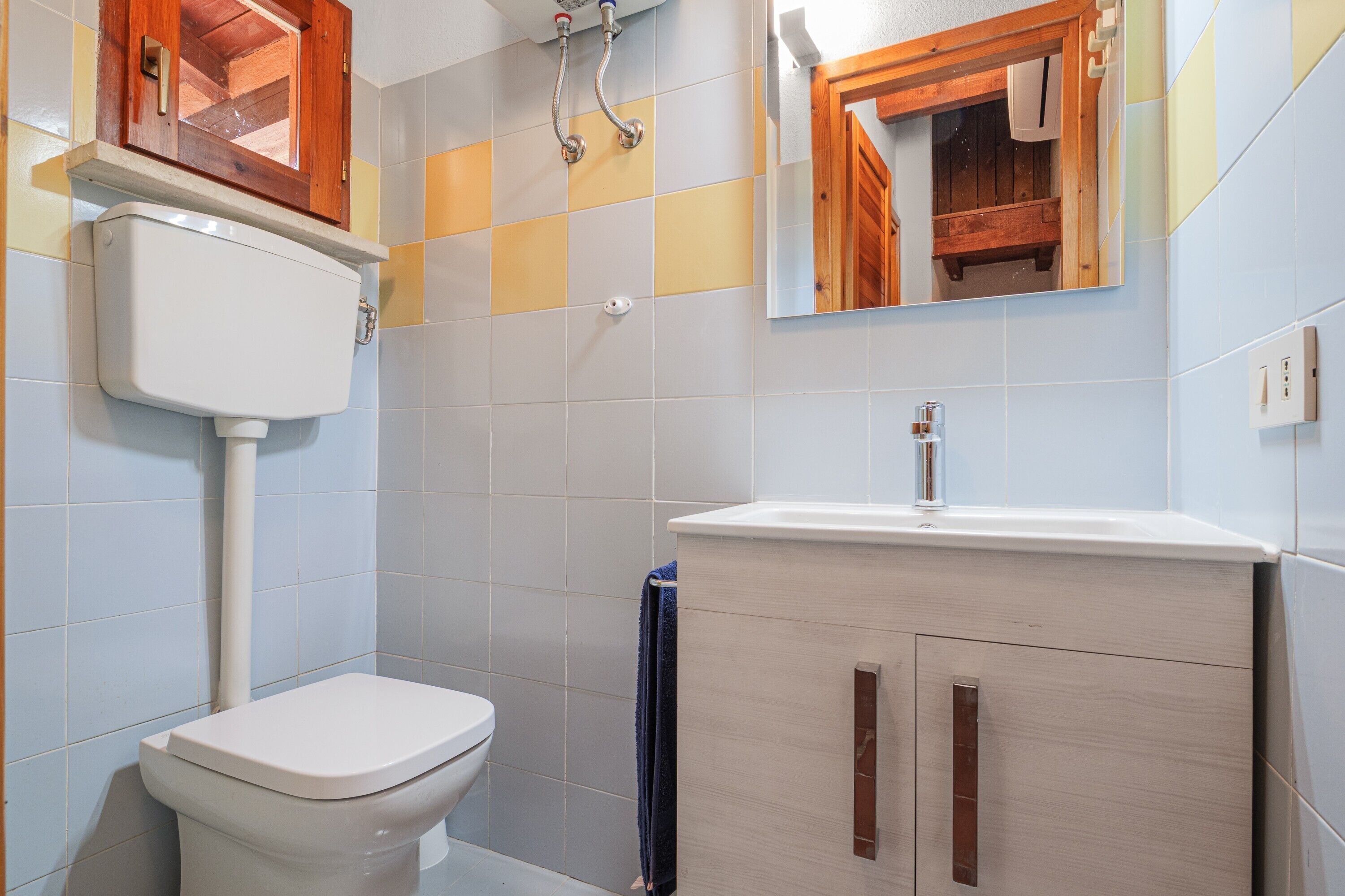 A bathroom with a toilet, a sink, and a mirror.