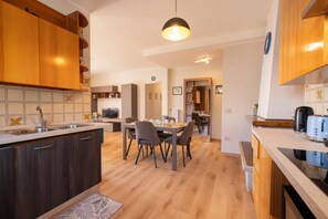 Eine moderne Küche mit Holzausstattung, einem Essbereich mit Stühlen, einem Einbauofen und einer Pendelleuchte.