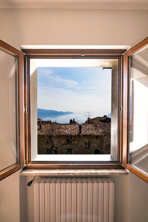 Ein Fenster mit Blick auf ein Gebäude mit einem Ziegeldach und einem weißen Heizkörper darunter.