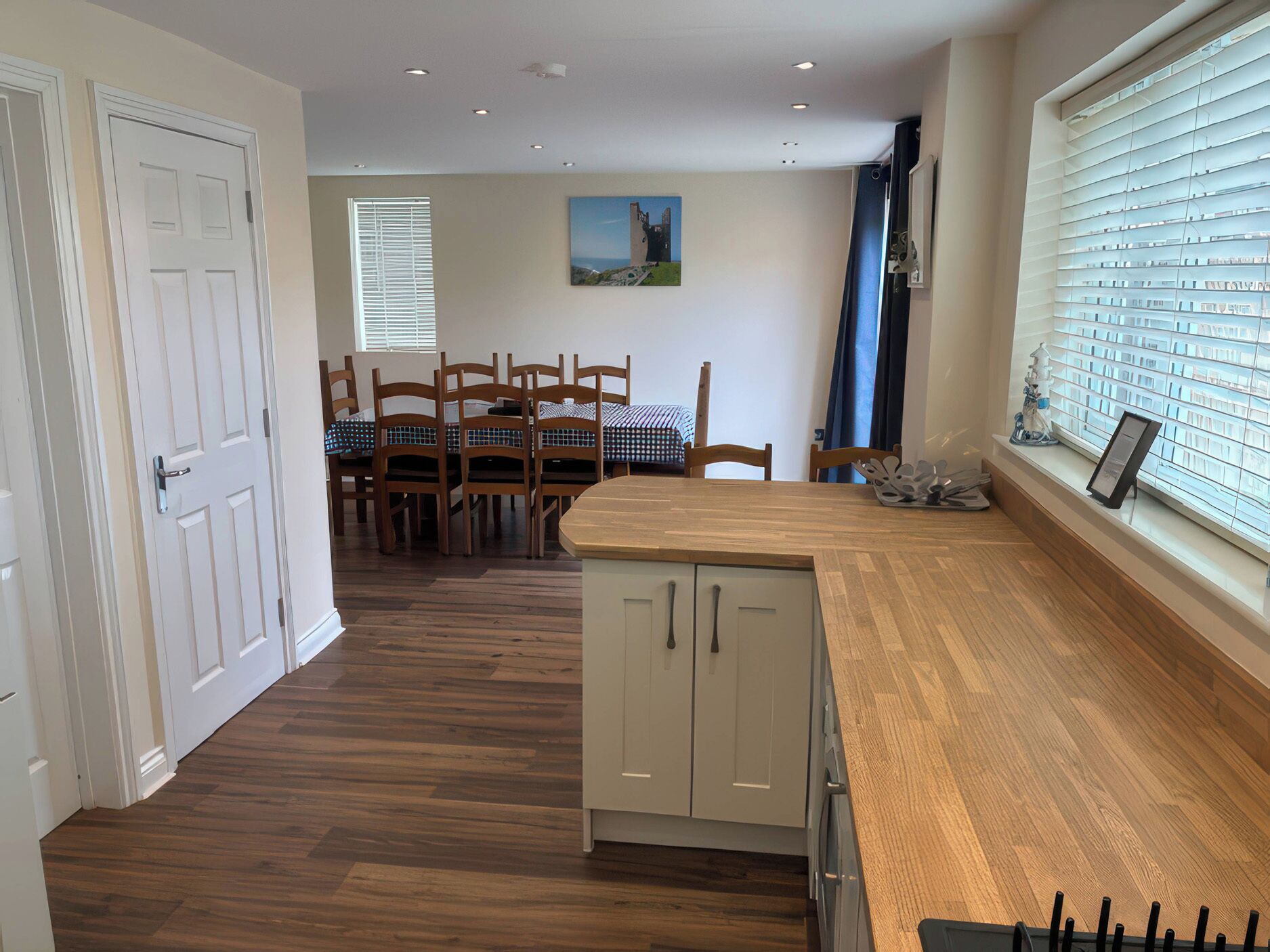 A kitchen with wooden cabinets, a dining table with chairs, and a window with blinds.