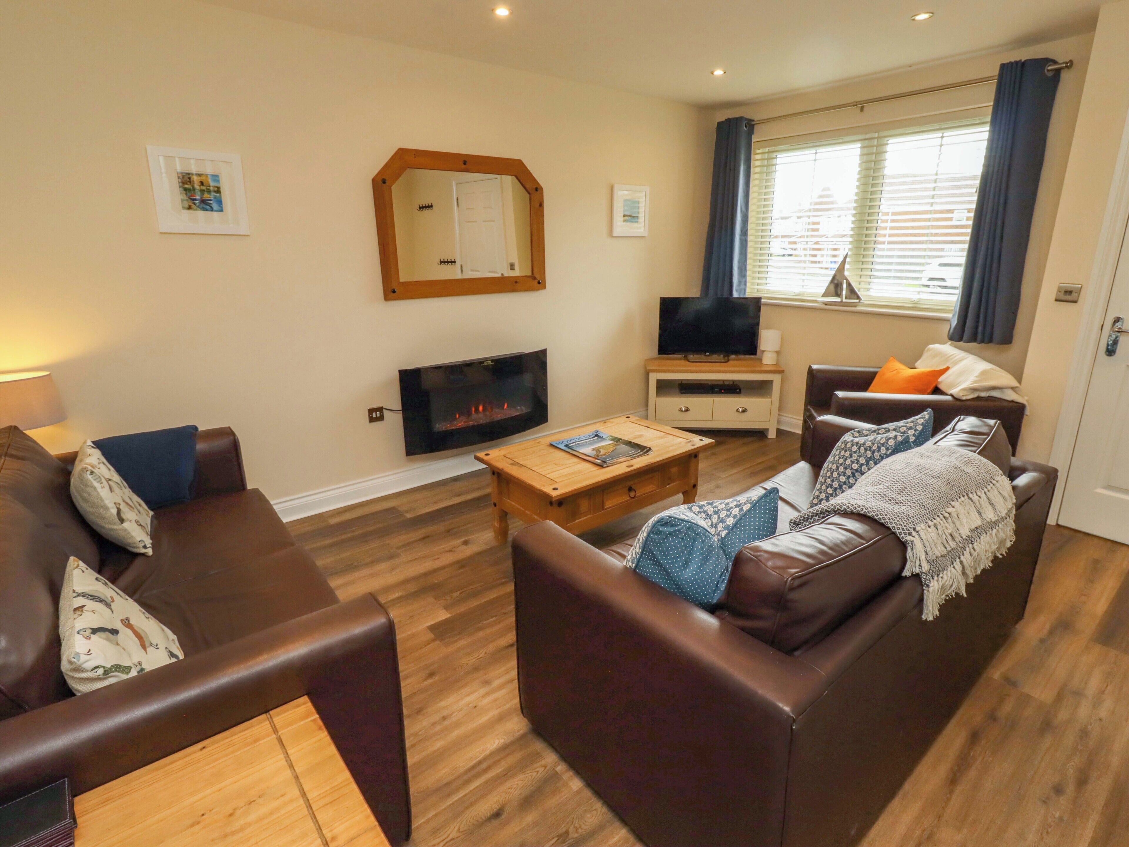A living room with a fireplace, a television, and two sofas.