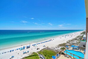 Blick auf einen Strand mit Swimmingpool und Liegestühlen.