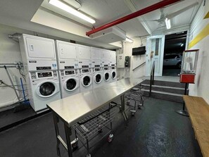 A laundry facility with multiple washing machines, a long table, and a fire extinguisher. - Relax and Enjoy: Pool, Self Check-In, and Parking (Carolina)