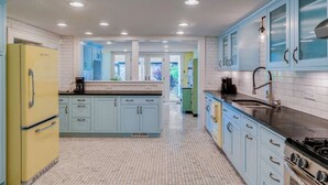 Una cucina con isola centrale, mobili azzurri, frigorifero giallo e piano cottura.