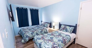 A bedroom with two beds, a nightstand, and a window with curtains. - NEW! Private Pool * BBQ * Steps to Beach (South Padre Island)
