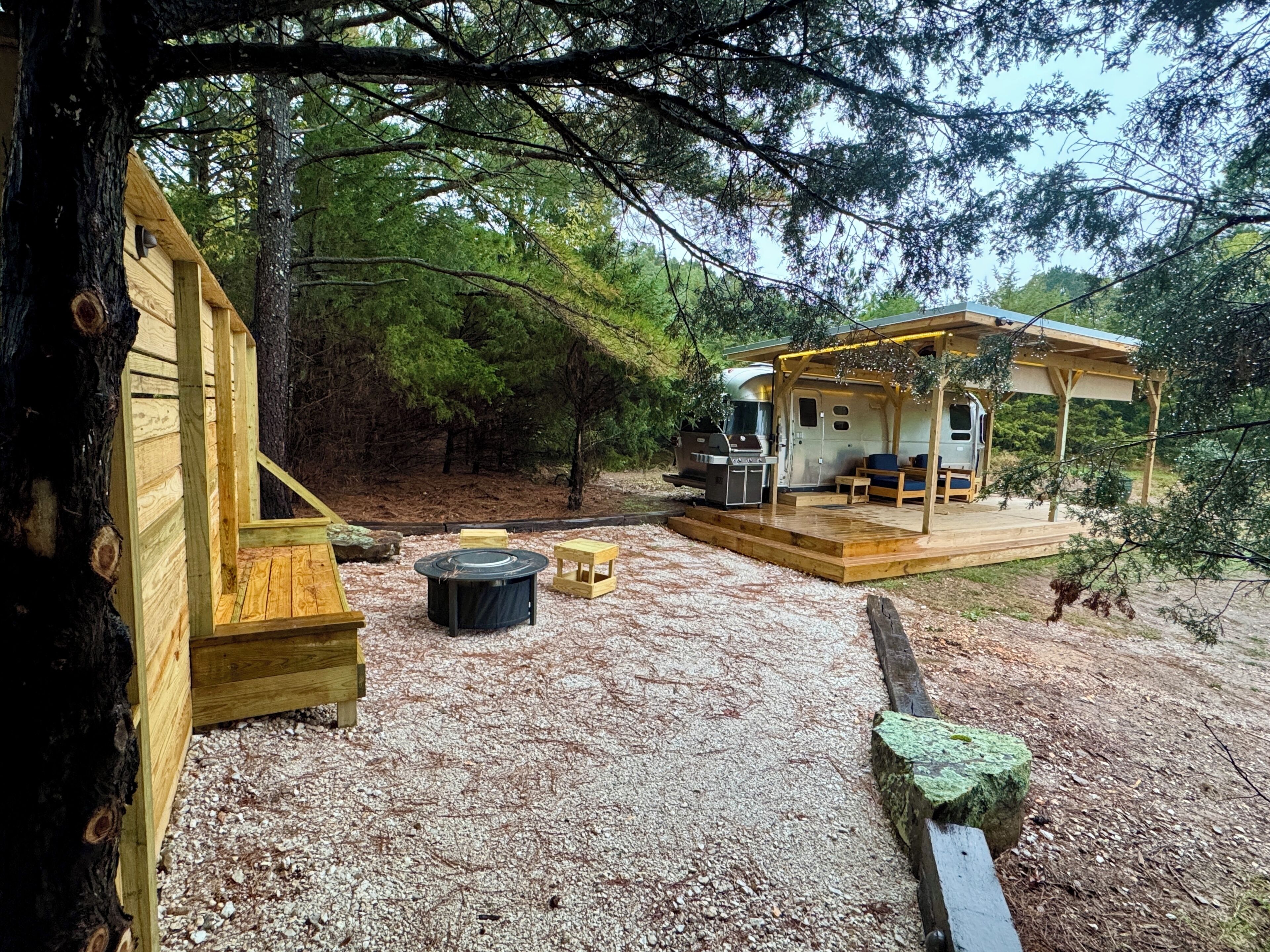 A cabin with a deck, a grill, and a covered seating area.
