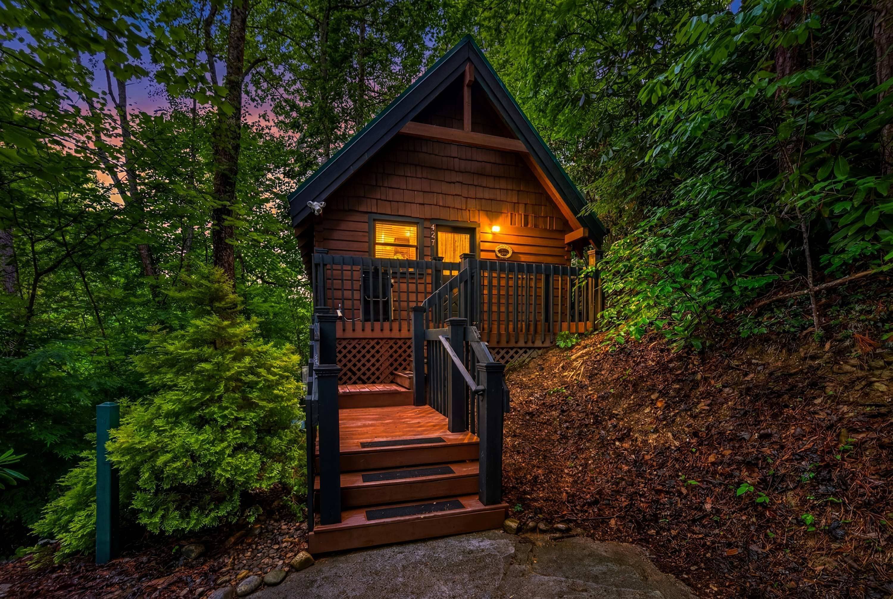 A cabin with a wooden exterior, a staircase, and a porch.
