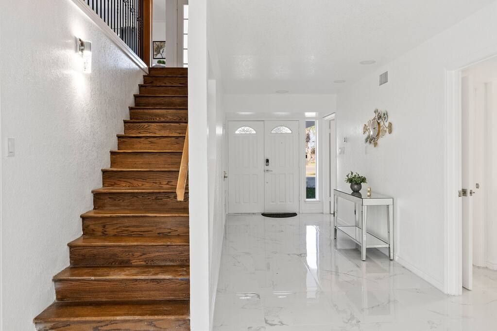 A staircase with wooden steps leading to a white interior space.