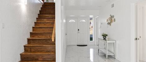 A staircase with wooden steps leading to a white interior space.