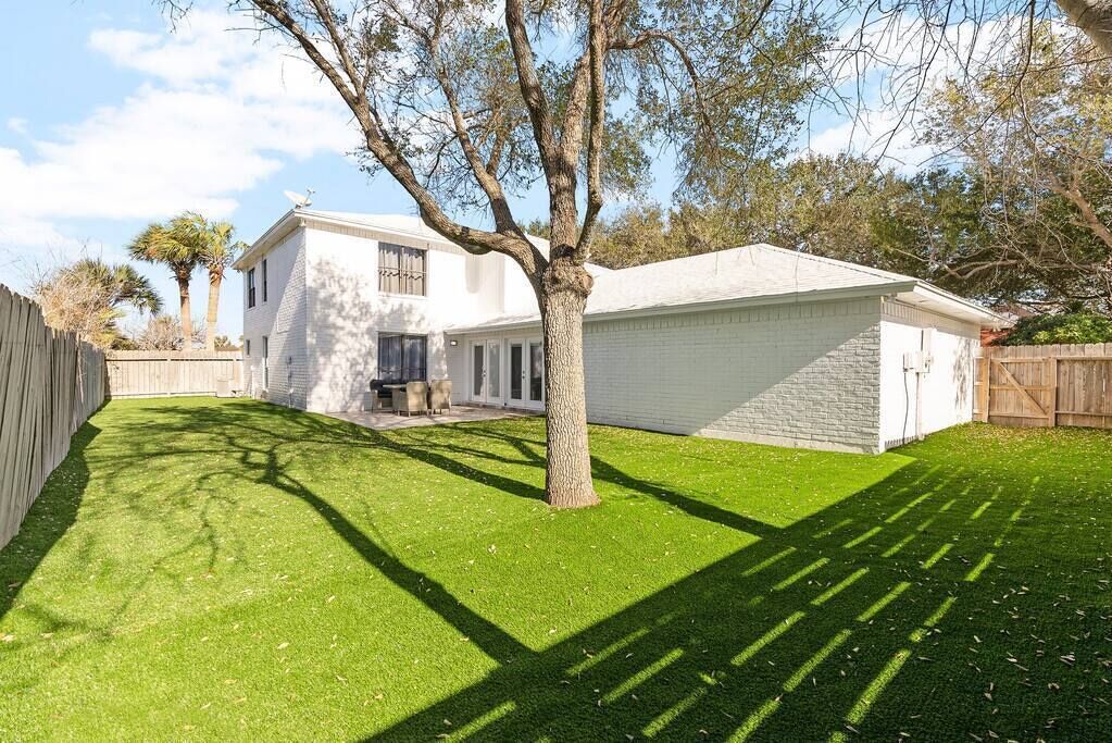 A residential property with a well-maintained lawn, a detached garage, and a two-story house with a brick facade.