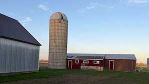 Une ferme avec un silo, une grange et un bâtiment en métal.