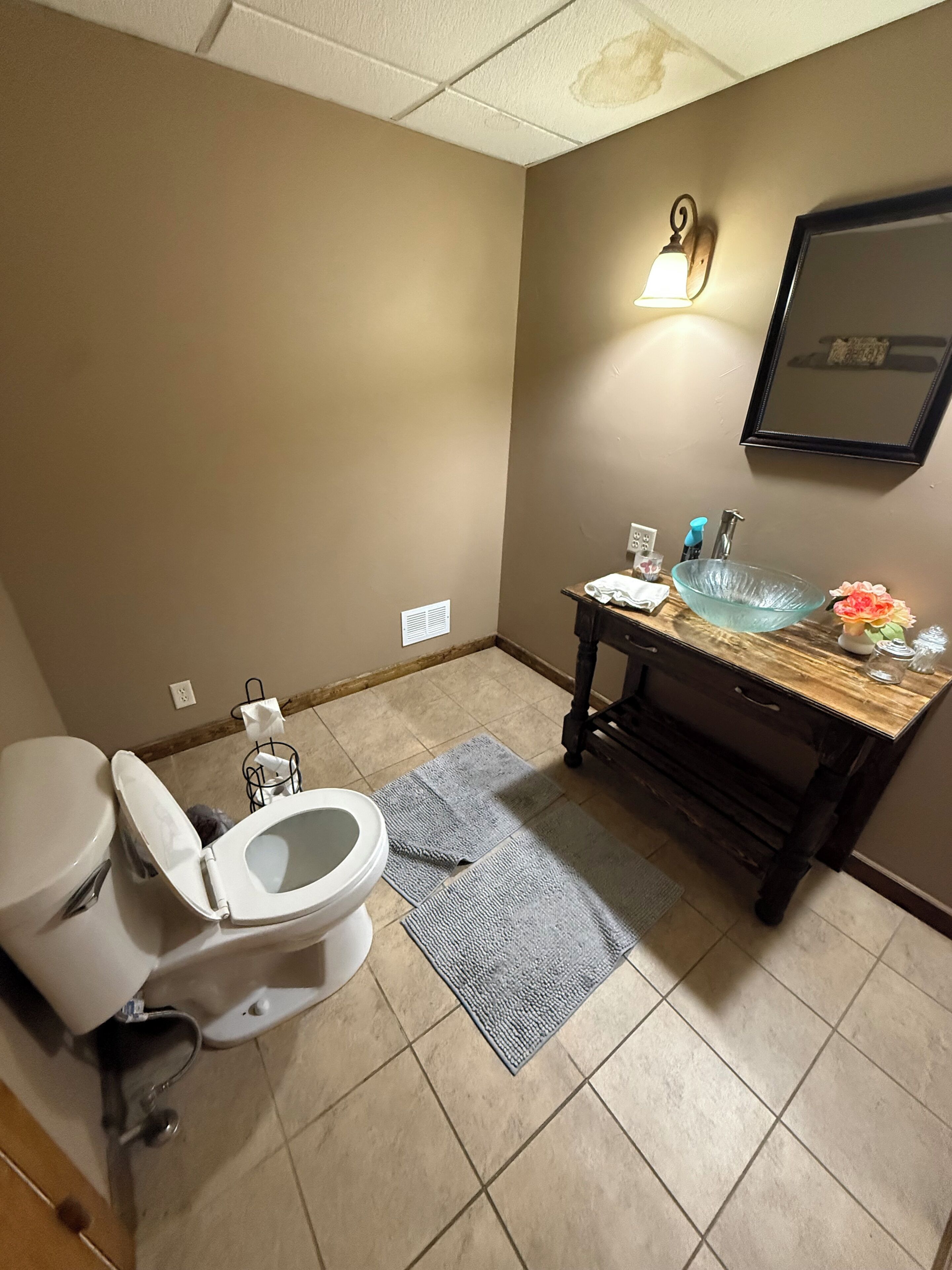 A bathroom with a toilet, sink, mirror, and a towel rack.