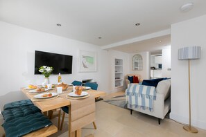 Ein modernes Wohnzimmer mit Essbereich, einer Couch, einem Fernseher und einer Stehlampe.