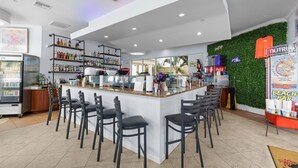 A bar area with a counter, bar stools, shelves with bottles, a refrigerator, and a wall with greenery. - Gulf View 2BR Suite Near Treasure Island Beach (Treasure Island)