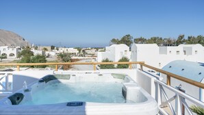 Un jacuzzi sur un balcon offrant une vue sur une ville côtière et une montagne en arrière-plan.