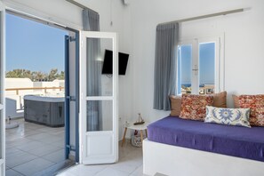 Un dormitorio con cama, televisor, bañera de hidromasaje y balcón con vistas.
