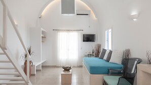 Un soggiorno moderno con un divano, una poltrona, una TV e una scala.