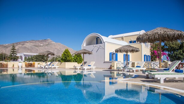 Area piscina con lettini, un edificio con una cupola e una montagna sullo sfondo.