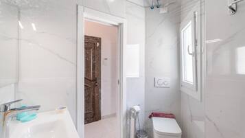 Un baño con lavamanos blanco, inodoro y zona de ducha.