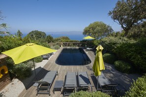 A pool with sun loungers and umbrellas, surrounded by greenery and a view of the sea. - Chambre d'hôtes L'Osso (Belvédère-Campomoro)