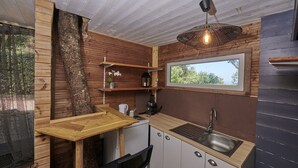 A compact kitchen with a wooden exterior, a built-in sink, and a hanging light fixture. - Double room-Deluxe-Ensuite with Shower-Sea view (Belvédère-Campomoro)