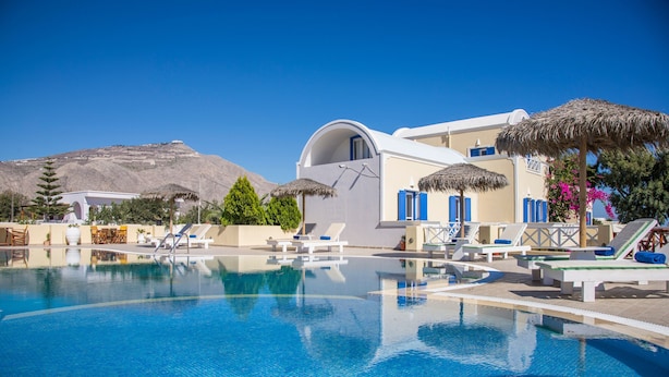 Un área de piscina con sillones de descanso, un edificio con cúpula y una montaña al fondo.