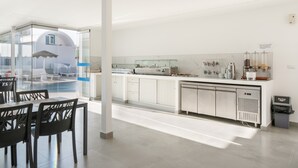 Cocina moderna con separador de vidrio, armarios blancos y vista a una zona de piscina.