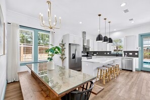 A modern kitchen with a central island, stainless steel appliances, and a dining area with stools. - Sun Drift: Private beach steps away, Heated pool, FREE golf cart, Bunk Rooms (Miramar Beach)