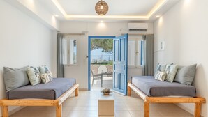 Une chambre avec deux lits, une petite table et une porte donnant sur l’extérieur.