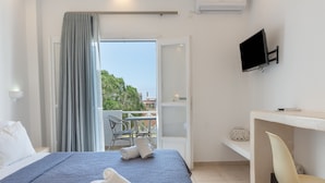 Hotelkamer met een bed, een bureau met stoel, een televisie en een balkon met tafel en stoelen.