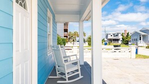 A porch with a rocking chair and a bench, a covered area, and a view of a residential street. - Circle View Cottage|Hot Tub·Shed Bar·Walk to Beach (Atlantic Beach)