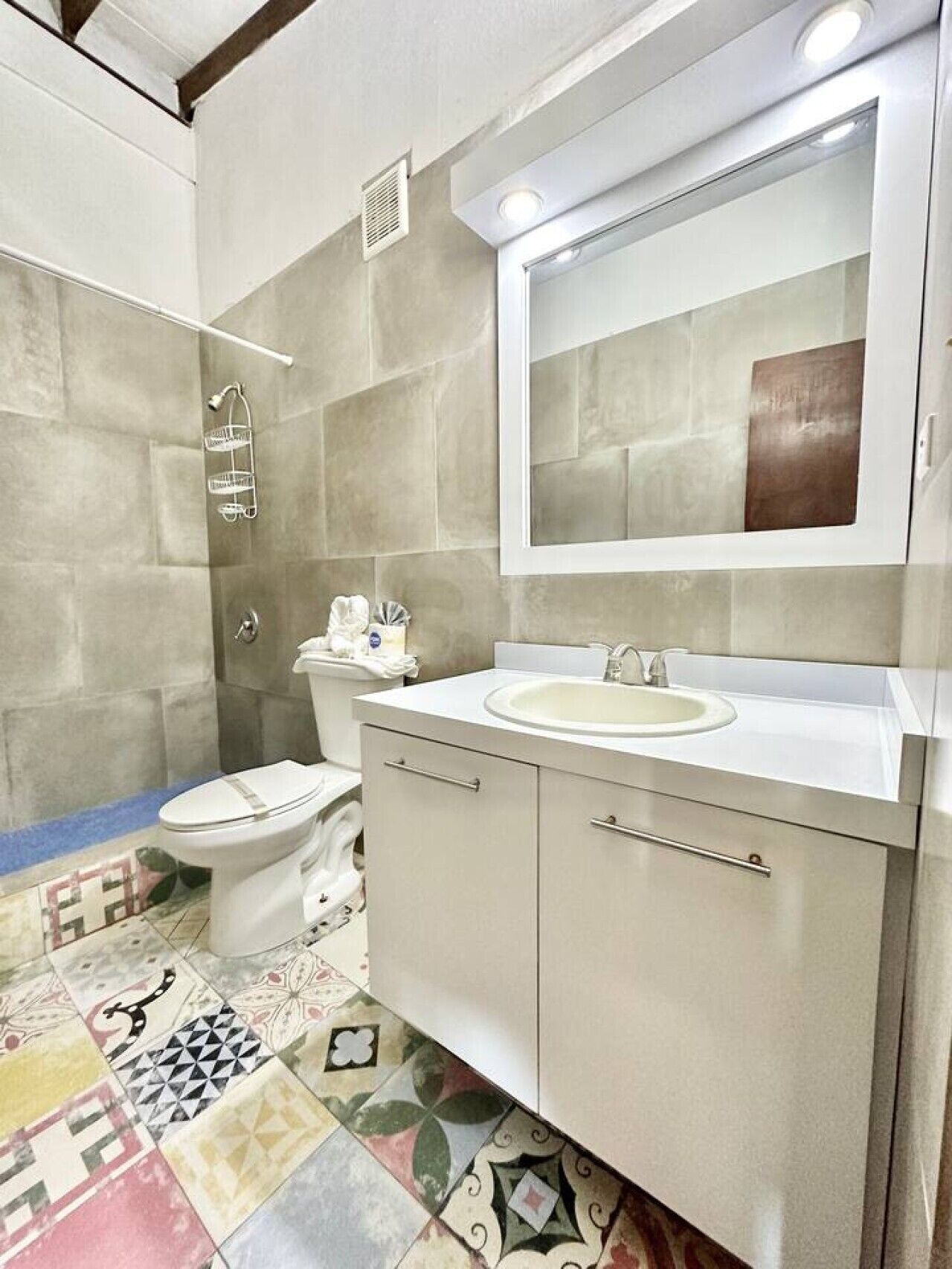 A bathroom with a shower, toilet, sink, and mirror.