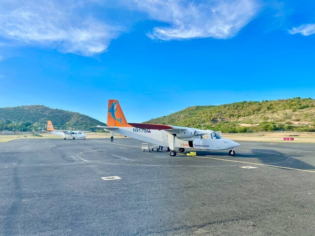 Ett flygplan står på en landningsbana med en klar himmel och ett kuperat landskap i bakgrunden.