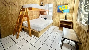 Een houten kamer met een stapelbed, een klein tafeltje en een raam met zonwering.