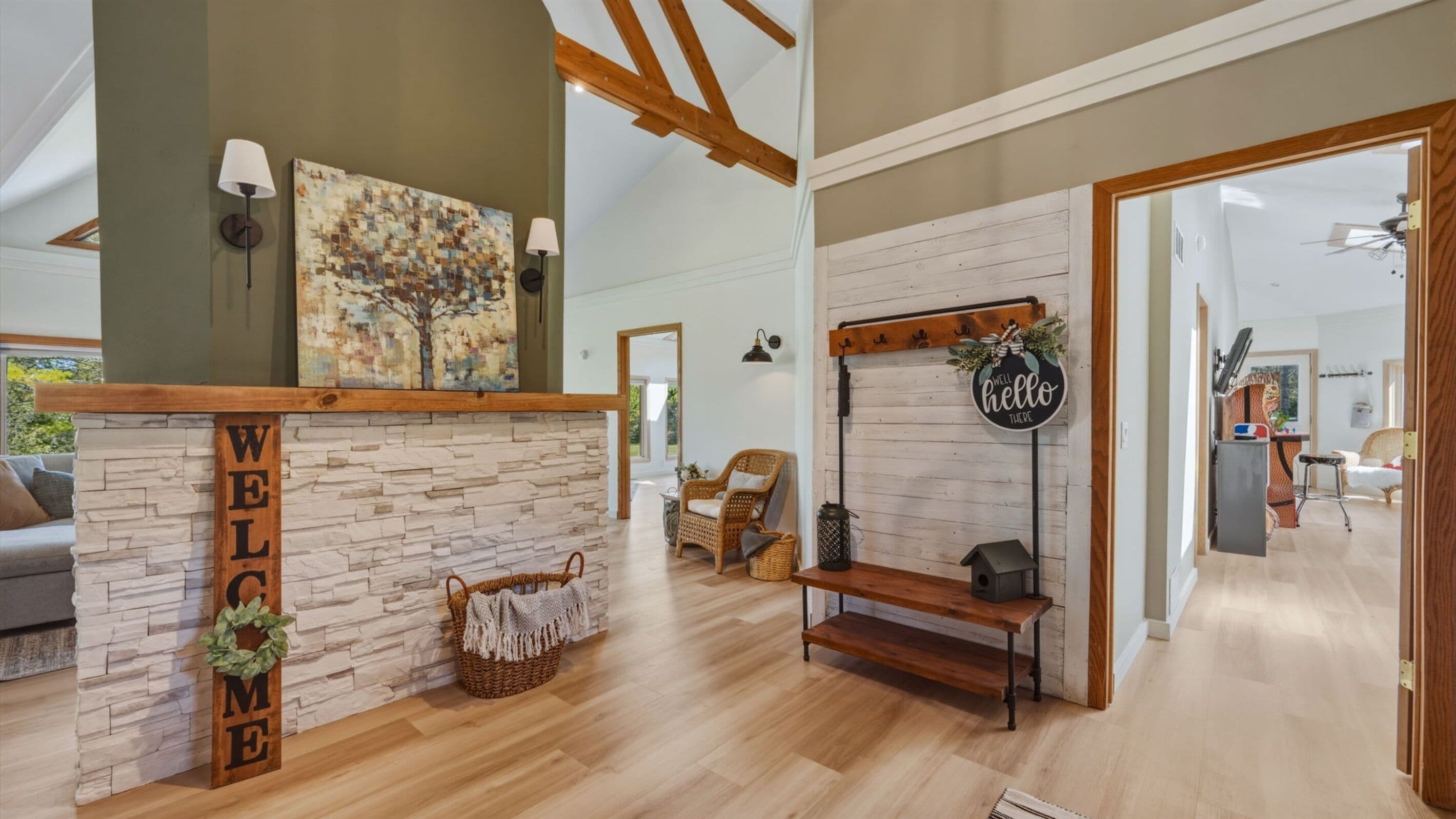 A spacious living area with a stone fireplace, a wooden bench, and a 'WELCOME' sign.