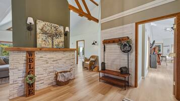 A spacious living area with a stone fireplace, a wooden bench, and a 'WELCOME' sign.