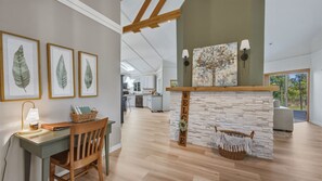 Une cuisine moderne avec des meubles blancs, une cheminée en pierre et des feuilles encadrées accrochées au mur.