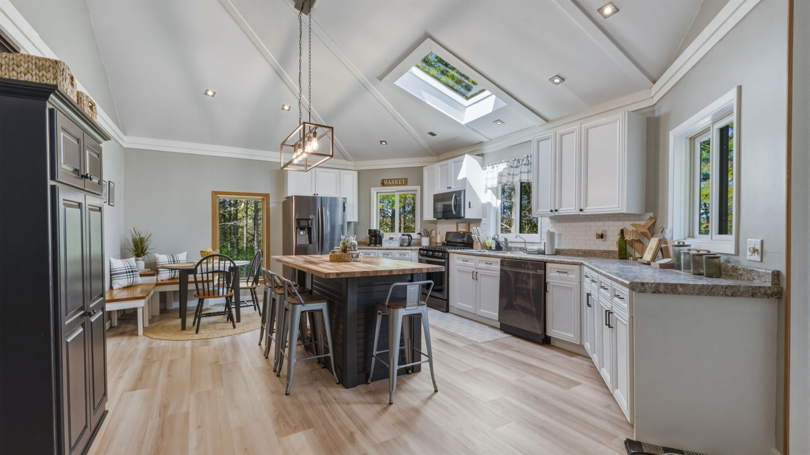 A spacious kitchen with a central island, white cabinetry, and a skylight.