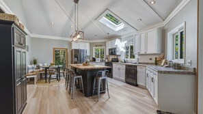 A spacious kitchen with a central island, white cabinetry, and a skylight.