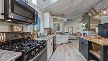 A modern kitchen with stainless steel appliances, a dining area with a wooden table, and a cozy seating area.