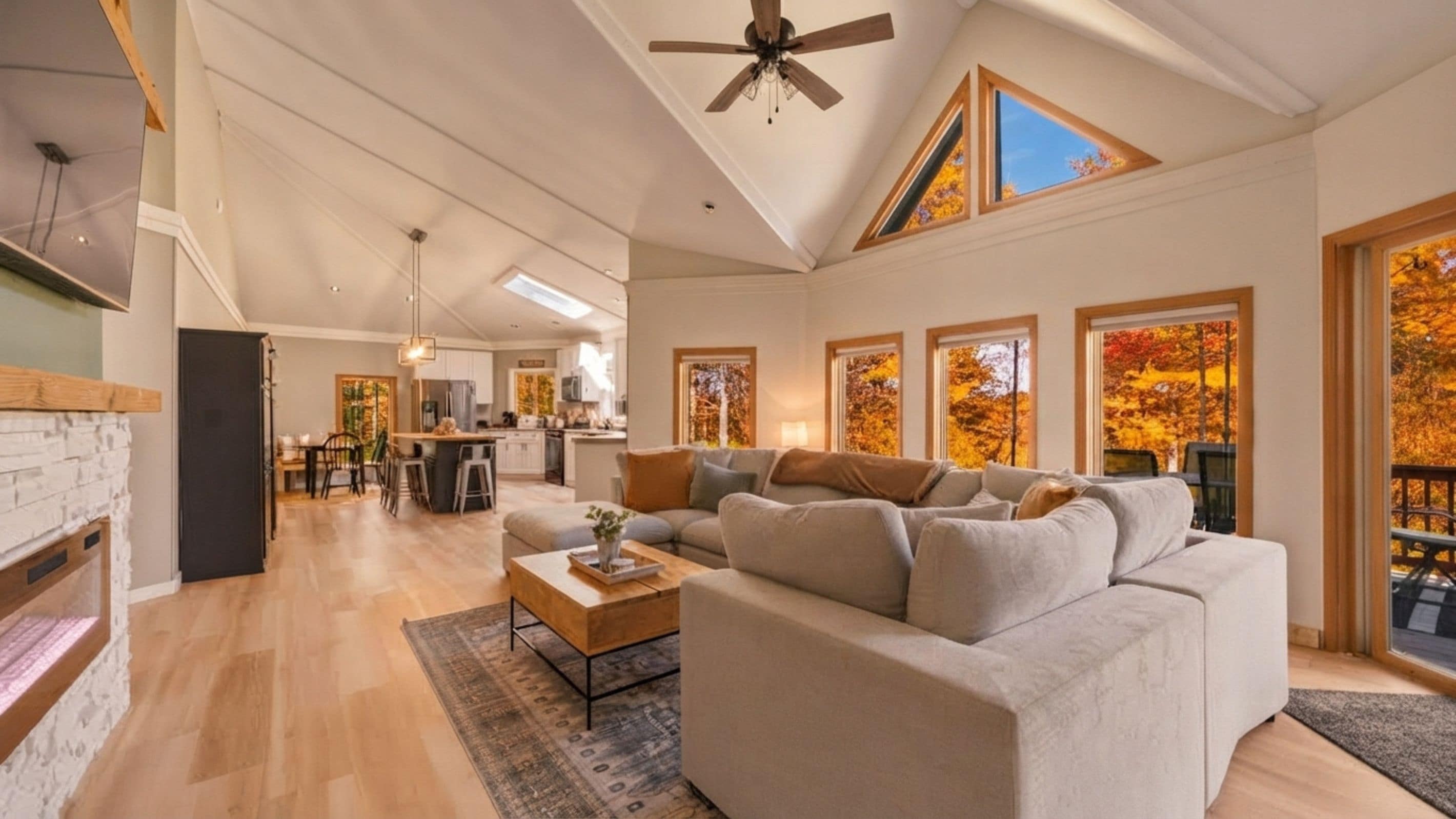 A spacious living room with a large sectional sofa, a fireplace, and a dining area in the background.