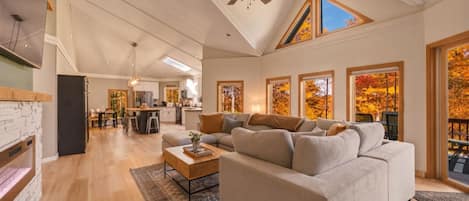 A spacious living room with a large sectional sofa, a fireplace, and a dining area in the background.